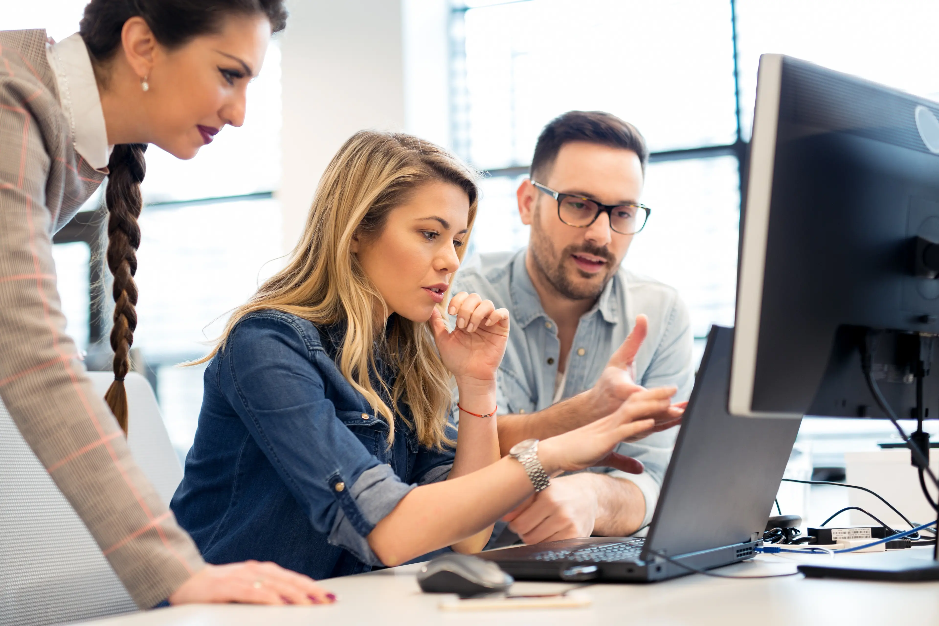 A group of colleages working together on a computer in an office