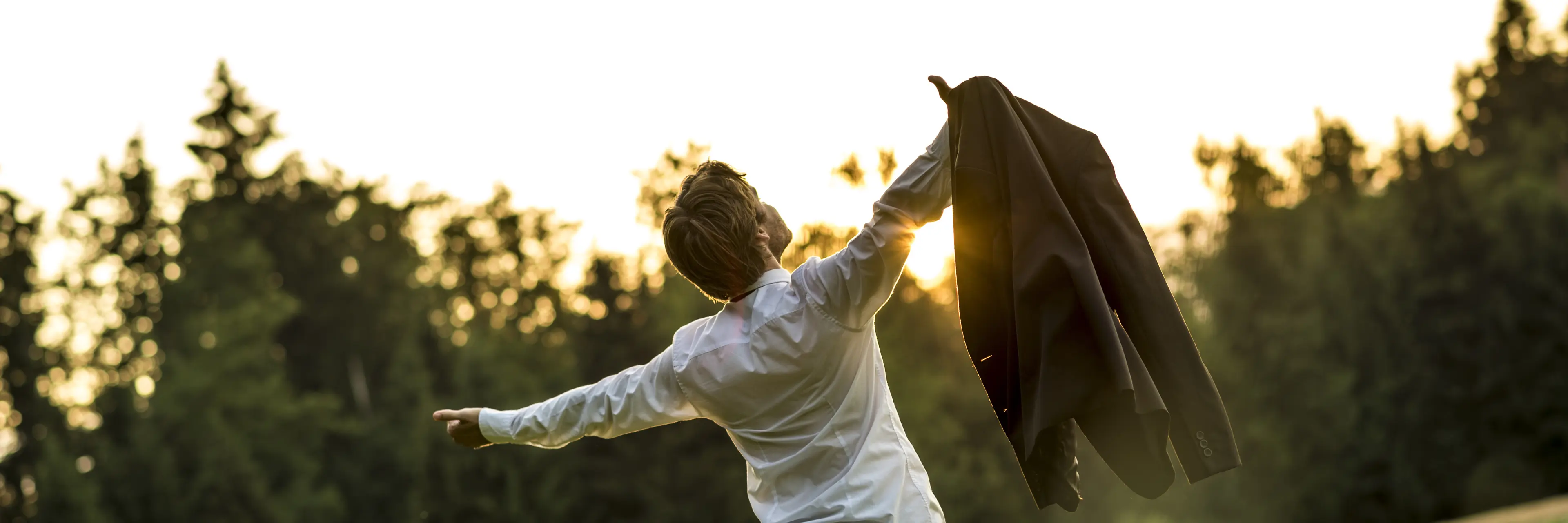 Man with his hands up watching the sun set 